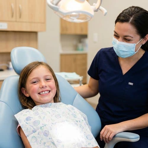 Smiling child in the dental chair with a caring team member during a pediatric visit